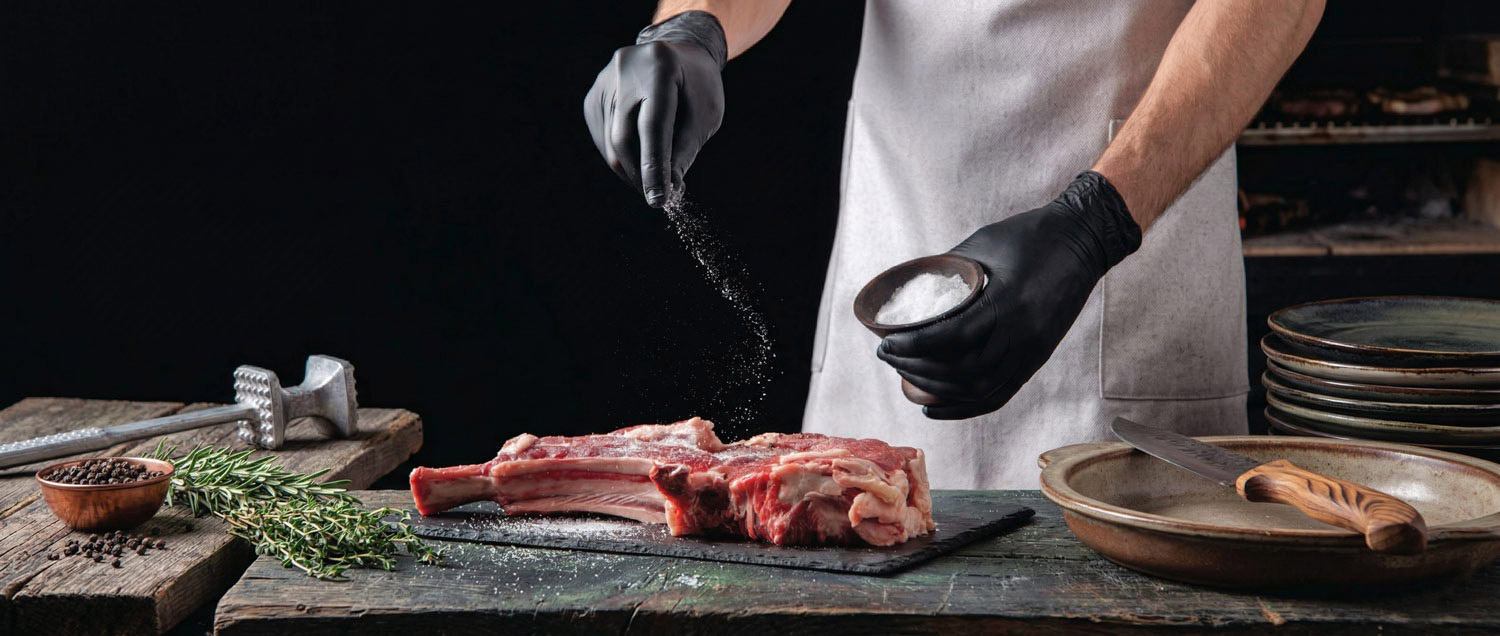 Chef seasoning a large cut of meat